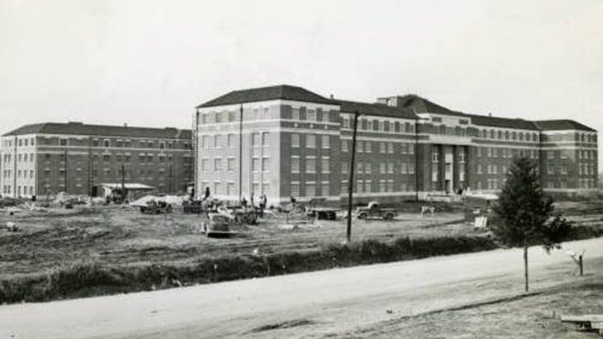 black and white building with people and vehicles